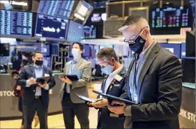  ?? Colin Ziemer / New York Stock Exchange via Associated Press ?? Traders work on the floor Wednesday. Stocks wobbled between small gains and losses in afternoon trading, hovering around record highs as investors remain cautiously optimistic about the economic recovery.