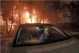  ??  ?? Tina Weeks evacuates after her neighbors’ house became fully engulfed by the Woolsey Fire in Oak Park, Calif., early Friday.