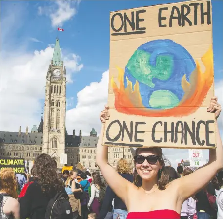  ?? WAYNE CUDDINGTON ?? Sydney Hutchison raises a sign on Parliament Hill as the Global Climate Protest takes to the streets Friday.