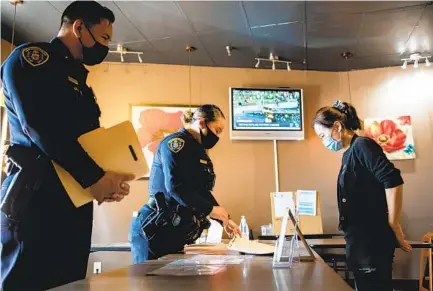  ?? KRISTIAN CARREON ?? San Diego police Officer Sharon Jung provides informatio­n about hate crimes to a worker at Go Go Sushi & Ramen in Mira Mesa.