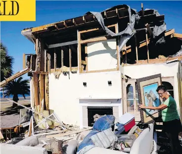  ?? DAVID GOLDMAN / THE ASSOCIATED PRESS ?? Marla Wood pulls a framed art piece out of the rubble of her damaged home in Mexico Beach, Fla., on Sunday.