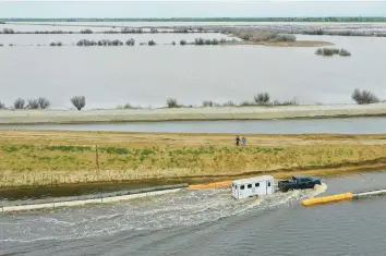  ?? PATRICK T. FALLON/GETTY-AFP ?? A pickup pulls a trailer along a flooded road last month in the Central Valley during flooding from winter storms in Tulare County, near Alpaugh, California. Roads and farms are being flooded where Tulare Lake once existed.