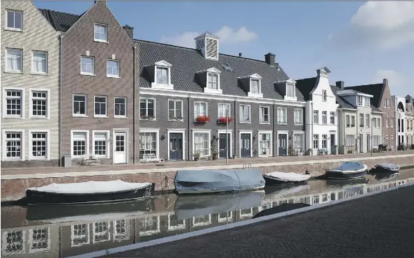  ?? JASPER JUINEN/BLOOMBERG ?? Houses line a canal in the Dutch town of in Maarssen. The Netherland­s ranks higher in household debt than Canada.