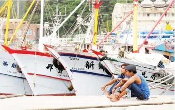  ?? — AFP photo ?? Fishermen rest near boats docked at the Patoutzu Fishing Harbour in Keelung as Typhoon Maria approaches northern Taiwan.