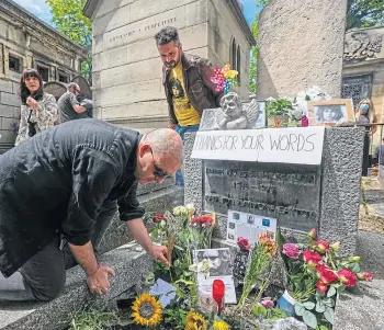  ??  ?? EMOTIONAL DAY: Fans of singer Jim Morrison at his tomb in Pere-Lachaise cemetery.