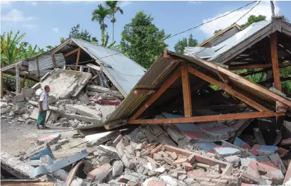  ?? Picture: AFP ?? SHOCK. A man looks at wrecked houses after a 6.4 magnitude earthquake hit Lombok yesterday.