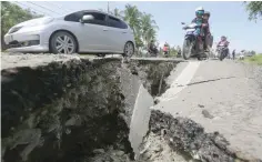  ?? — Reuters ?? Motorcycli­sts pass a damaged section of a road following an earthquake in Meureudu, in the northern province of Aceh.