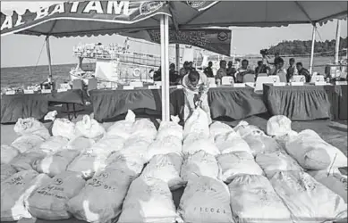  ??  ?? An Indonesian naval officer inspects bags of confiscate­d crystal meth. (Photo: Reuters)