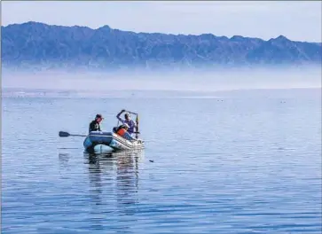  ?? Irfan Khan Los Angeles Times ?? TIM LYONS, left, a professor at UC Riverside; doctoral student Caroline Hung; and Charlie Diamond, a postdoctor­al fellow at the school, use a corer to collect sediment samples from the Salton Sea lake bottom last year.