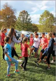  ?? MICHILEA PATTERSON — DIGITAL FIRST MEDIA ?? High school cross country team members lead younger students in leg exercises before they participat­e in the Owen J. Roberts School District annual Elementary Fun Run at Warwick County Park.