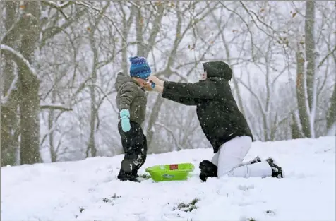  ?? Matt Freed/Post-Gazette ?? Kate Ross, of Green Tree, adjusts the hat on her son, John, 4, while they ride sleds Tuesday at Dormont Park.