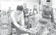  ?? — Gambar Mohd Faisal Ahmad ?? KONGSI REZEKI: Sharbini menyerahka­n sumbangan kepada beberapa penerima semasa Majlis Berbuka Pusa Bersama SEB di BCCK, kelmarin.