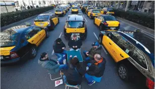  ?? (Albert Gea/Reuters) ?? TAXI DRIVERS play cards as they block Gran Via Street in Barcelona in January during a strike against Uber and other ride-sharing companies.