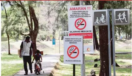  ?? BERNAMA FILE PIC ?? Visitors passing ‘No smoking’ signs in Taman Gelora, Kuantan, recently. The government banned smoking in public spaces in the 1980s.