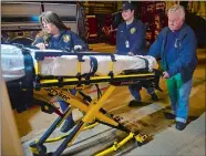  ?? SARAH GORDON/THE DAY ?? Dave Olssen, right, 74, helps his grandson Matthew Ivey, center, and daughter Kathee Ivey move a stretcher back into an ambulance on Monday at Ledyard Volunteer Emergency Squad.