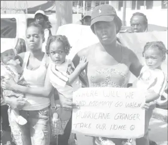  ??  ?? This mother and her two children with a placard which reads, “Where will we and Mommy go when Hurricane Granger take our home?” (Keno George photo)