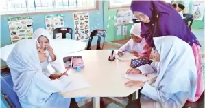  ??  ?? SARIMAH meneliti salah seorang murid dalam proses pengajaran dan pembelajar­an.