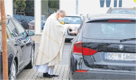  ?? FOTO: WOLFGANG LUTZ ?? Der „Leib Christi“wurde an die Autotür gebracht, wo er mittels einer Schale von den Katholiken in Empfang genommen wurde.