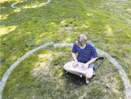  ?? JOSHUAABIC­KEL/AP ?? A student works while sitting inside a painted circle, to keep students socially distanced, during the first day of fall classes at Ohio State University in Columbus, Ohio.