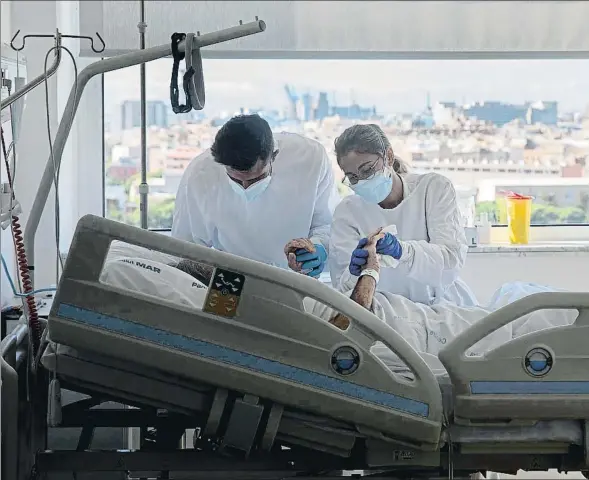  ??  ?? Pol, estudiante de enfermería, y Ana, enfermera, atienden a un paciente en la unidad de infeccioso­s del hospital del Mar de Barcelona