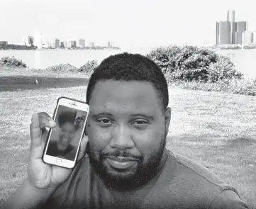  ?? CARLOS OSORIO/AP ?? With the cities of Windsor, Ontario, Canada, left, and Detroit, right, seen in the background, Quintin Sweat Jr., shows his fiancee, Renee Harrison, on his phone on Belle Isle in Detroit. Sweat and Harrison are separated by the border.