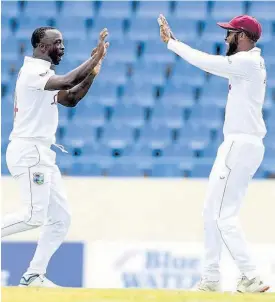  ?? FILE ?? West Indies’ bowler Kemar Roach reacts with captain Kraigg Brathwaite (right) after one of the three wickets he claimed to help reduce Sri Lanka to 169 all out on Day One of the first Test in Antigua on Sunday, March 21.