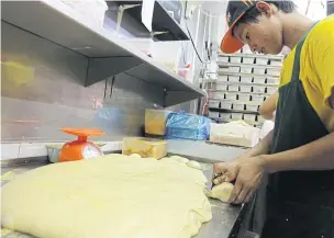  ?? WICHAN CHAROENKIA­TPAKUL ?? A worker cuts a piece of dough at a bakery. Recipes are being modified to cut the use of artificial trans fats before they are banned in Thailand from Jan 9.