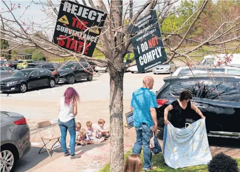  ?? ELIJAH NOUVELAGE/GETTY ?? Signs are seen in a tree at a protest against masks, vaccines and vaccine passports outside the headquarte­rs of the Centers for Disease Control and Prevention in Atlanta.