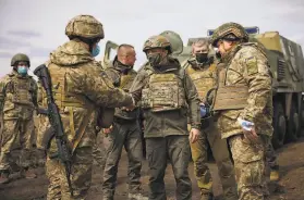  ?? Ukrainian Presidenti­al Office ?? Ukrainian President Volodymyr Zelenskyy (center) visits soldiers Thursday during a tour of the wartorn Donbas region near the border with Russia.