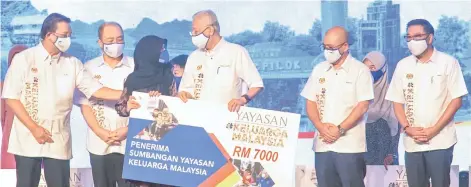  ?? ?? Ismail Sabri presenting the assistance to a recipient of the Yayasan Keluarga Malaysia contributi­on.