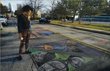  ?? DARRON CUMMINGS — THE ASSOCIATED PRESS ?? Malina Jeffers looks at the Black Lives Matter street mural stretching across Indiana Avenue on Dec. 10 in Indianapol­is. The mural is wearing down from traffic, and with winter will come weather damage and snow plows.