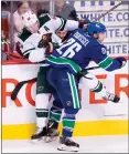  ?? Canadian Press photo ?? Vancouver Canucks left wing Antoine Roussel puts Minnesota Wild defenceman Ryan Suter into the boards during third period NHL hockey action in Vancouver, Monday.