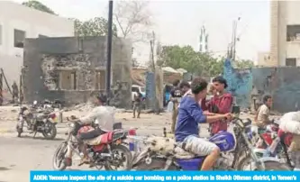  ?? — AFP ?? ADEN: Yemenis inspect the site of a suicide car bombing on a police station in Sheikh Othman district, in Yemen’s government-held second city Aden.