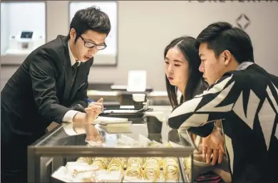  ?? BLOOMBERG VIA GETTY IMAGES ?? An employee assists customers at a Chow Tai Fook Jewellery Group Ltd store in the Central district of Hong Kong.