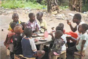 ?? Al-Hadji Kudra Maliro / Associated Press ?? Children eat outside the home of Marie Charline Mutsuva in eastern Congo. Hundreds of children have been orphaned by rebel attacks. “I felt compelled to help them,” she said.