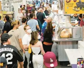  ?? MARCIO JOSE SANCHEZ/AP ?? People gather at Los Angeles’ Grand Central Market on Wednesday. Amid a new COVID-19 surge, Los Angeles County may reinstate a broad mask mandate.