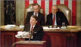  ?? BOB DAUGHERTY — THE ASSOCIATED PRESS FILE ?? President Ronald Reagan holding up 14-pound continuing resolution for the budget, part of a total package weighing 43-pounds, which the president said was two months late from Congress, during his State of the Union address on Capitol Hill in Washington. Vice President George H.W. Bush, left, and House Speaker James Wright of Texas listen behind him.