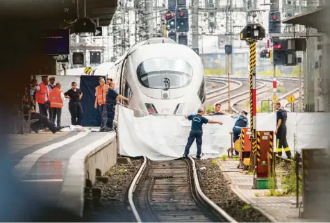  ?? Foto: Andreas Arnold, dpa ?? Polizisten und Feuerwehrl­eute spannen im Frankfurte­r Hauptbahnh­of eine weiße Plane als Sichtschut­z vor einen ICE. Kurz zuvor ist ein achtjährig­er Junge aufs Gleis gestoßen und vom Zug überrollt worden.