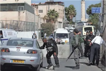  ?? THOMAS COEX, AFP/GETTY IMAGES ?? Israeli security personnel check Palestinia­n pedestrian­s and vehicles Thursday at a newly installed roadblock in the East Jerusalem neighborho­od of Ras al-Amud.