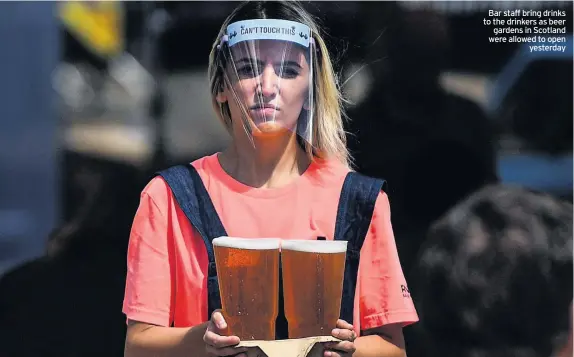  ??  ?? Bar staff bring drinks to the drinkers as beer gardens in Scotland were allowed to open yesterday