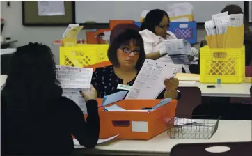  ?? PHOTOS BY THE ASSOCIATED PRESS ?? Lydia Harris, a temporary worker at the Sacramento Registrar of Voters, looks over a mail-in ballot before it is sent to be counted in Sacramento in 2014. Many mistakes were discovered with mail-in ballots for March’s presidenti­al primary.