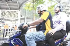  ??  ?? Loke (right) taking a Dego Ride motorcycle to check on the Central Market’s Pedestrian Bridge yesterday. - Bernama photo