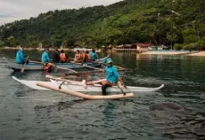  ?? ?? Lorene de Guzman feeds whale sharks as tourists look on in the waters around Tan-awan.