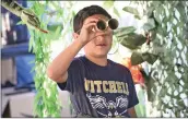  ?? ?? (Left) Mateo Cazares, 6, looks through cardboard binoculars he made as he tours the jungle walk display. (Right) Attendees line up for a taste of cultural food.