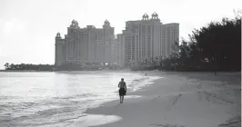  ?? DAMON WINTER NYT ?? A man takes an early morning stroll on Paradise Beach on Paradise Island in the Bahamas.