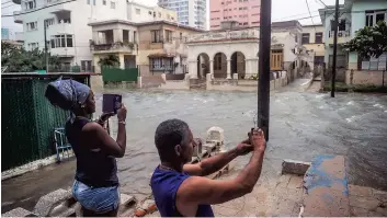  ?? PHOTO AFP ?? Des Cubains prennent des photos de la montée des eaux dans les rues de La Havane.
