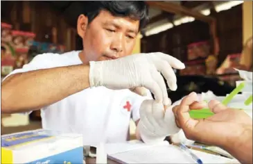  ?? TANG CHHIN SOTHY/AFP ?? A health worker takes a sample of blood from a patient for a malaria test at his home in Pailin province in 2012.