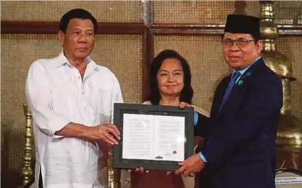  ?? REUTERS PIC ?? President Rodrigo Duterte (left) and Moro Islamic Liberation Front chairman Murad Ebrahim showing a document containing a signed autonomy law during a ceremony at the presidenti­al palace in Manila yesterday.
