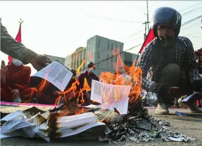  ??  ?? Varios antigolpis­tas queman la Constituci­ón de Myanmar, ayer, en Mandalay