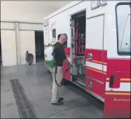  ?? MELISSA SCHUMAN — MEDIANEWS GROUP ?? Quick Response CEO Vince Laurenzo demonstrat­es the use of an electrosta­tic backpack sprayer on one of the Troy fire department trucks.